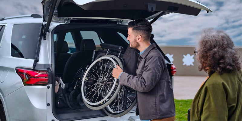 Man placing a wheelchair into Chevy Traverse