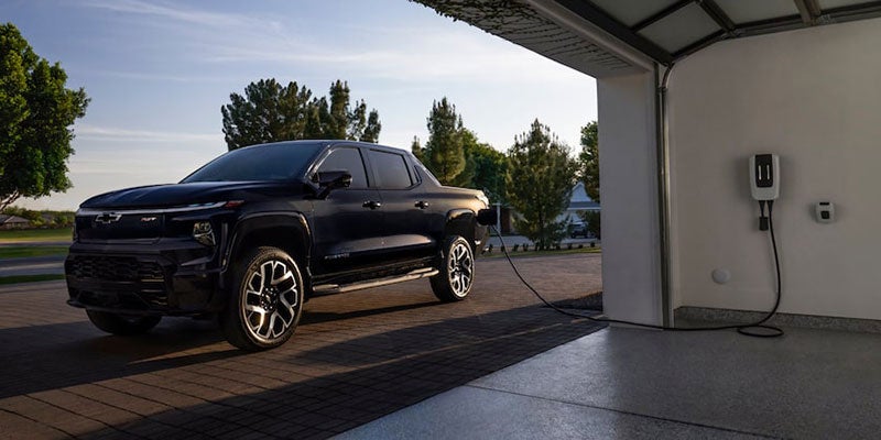 A 2024 Chevrolet Silverado EV is connected to an electric vehicle charging station, showcasing its electric capabilities.